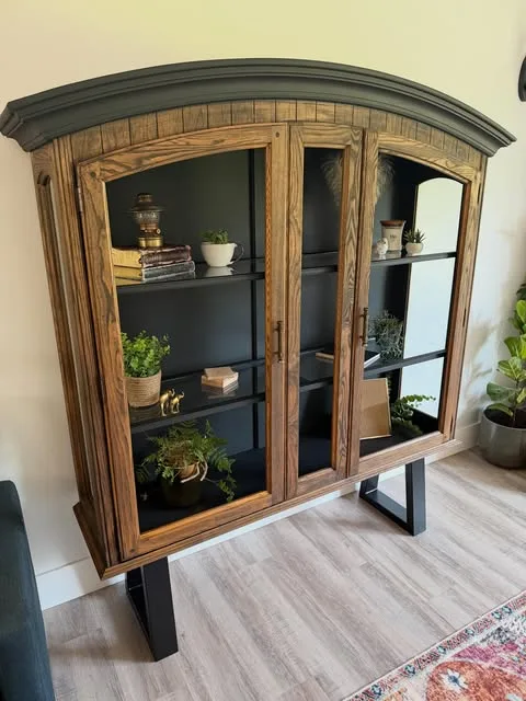 Arched wood display cabinet with a dark painted top and base