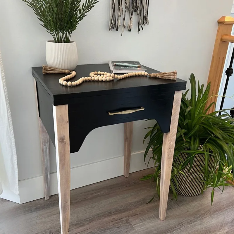 Side table painted black with natural wood legs